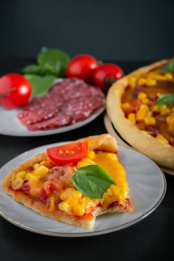 Siyah arka planda ısırılmış bir pizza. Koyu arkaplanda lezzetli bir İtalyan pizzası var. Akdeniz mutfağının özgün ulusal yemeği.