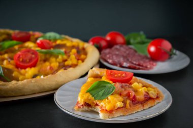 Siyah arka planda ısırılmış bir pizza. Koyu arkaplanda lezzetli bir İtalyan pizzası var. Akdeniz mutfağının özgün ulusal yemeği.