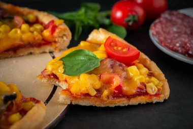 Siyah arka planda ısırılmış bir pizza. Koyu arkaplanda lezzetli bir İtalyan pizzası var. Akdeniz mutfağının özgün ulusal yemeği.