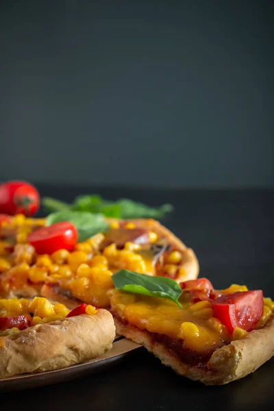 Pizza on a gray background. Authentic national dish of Mediterranean cuisine. Fresh pizza with cheese and cherry tomatoes on a round board, sliced slice. Vertical photo