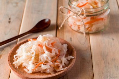 Hafif ahşap arka planda ev yapımı lahana turşusu. Ev yapımı mayalanmış lahanalı cam kavanoz. Eko gıda, sağlıklı beslenme eğilimi.