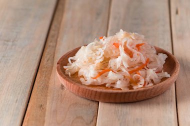 Tahta tabakta ev yapımı lahana turşusu. Hafif arka planda havuçlu mayalanmış lahana. Eko gıda, sağlıklı beslenme eğilimi. Metnin için yer.