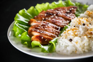 Ev yapımı yemek, beyaz pirinç ve biberli teriyaki tavuğu ve siyah arka plan..