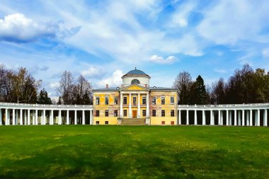 Baharda yeşil ağaçların arka planında güzel, eski bir malikane. Mavi gökyüzünün arka planında sütunları olan eski bir malikane.