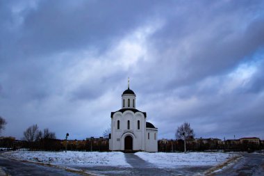 Kışın bulutlu bir gökyüzüne karşı küçük beyaz Hıristiyan kilisesi. Kışın küçük beyaz Hıristiyan kilisesi