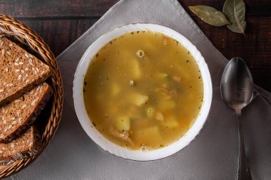 Kahverengi arka planda bir tabakta balık çorbası. Diyet balık çorbası ve tahıl ekmeği masada, düz yatıyordu.
