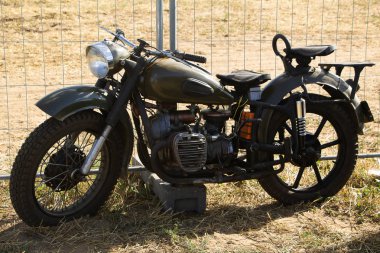 Güneşli bir yaz gününde moto kampında klasik bir motosiklet. Eski bir motosiklet kamp alanında duruyor..