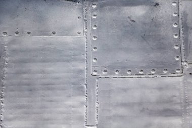 Uçak derisi yakın mesafede. Gri metalin üzerindeki perçinler. Tasarım için arkaplan.