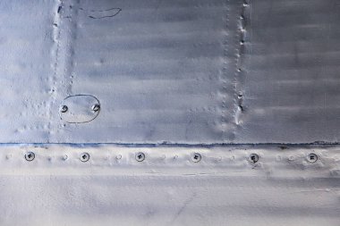 Uçak derisi yakın mesafede. Gri metalin üzerindeki perçinler. Tasarım için arkaplan.