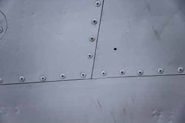 Uçak derisi yakın mesafede. Gri metalin üzerindeki perçinler. Tasarım için arkaplan.