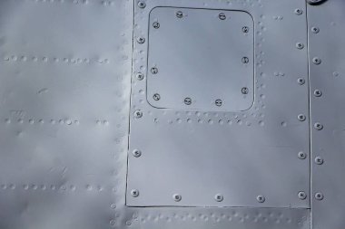 Uçak derisi yakın mesafede. Gri metalin üzerindeki perçinler. Alüminyum doku