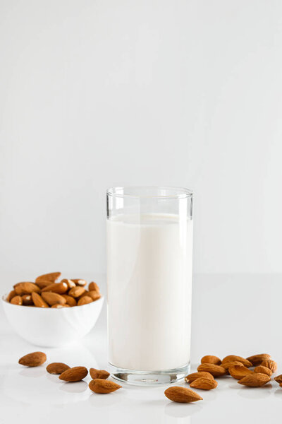 Стакан миндального молока на белом фоне. Без лактозы растительное диетическое молоко. Безглютеновый миндальный напиток на синем фоне. Super Food - стакан миндального молока для здорового питания. Трендовая еда, вертикальное фото. Место для текста
.