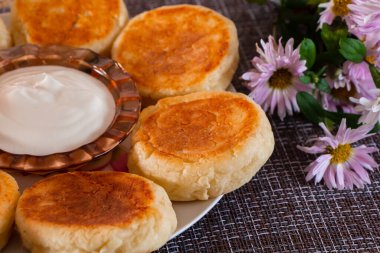 Kahverengi arka planda tabakta iştah açıcı peynirli kekler. Kahvaltı için bir tabak süzme peynir..