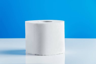 Mavi arka planda bir rulo tuvalet kağıdı. Gerekli malların panik içinde alınması. Dünyadaki koronavirüs salgını..