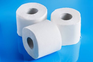 Mavi arka planda üç rulo tuvalet kağıdı. Gerekli malların panik içinde alınması. Dünyadaki koronavirüs salgını..