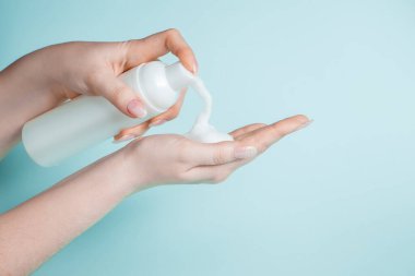 Genç bir kadın ellerini dezenfekte etmek için antibakteriyel sabun kullanıyor. Coronavirus önleme, sağlık koruma kavramı.