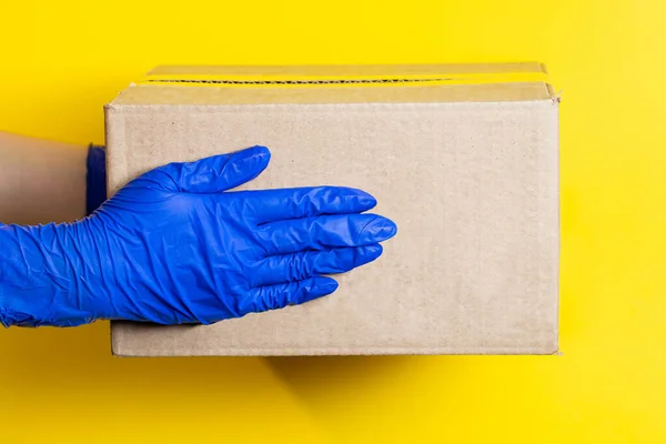 Egy Orvosi Gumikesztyűs Férfi Egy Csomagot Szállít Sárga Alapon Áruk — Stock Fotó