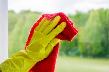 Cam temizleme ve ev temizliği. Sarı eldivenli hizmetçi kirli camları yıkıyor ve siliyor..