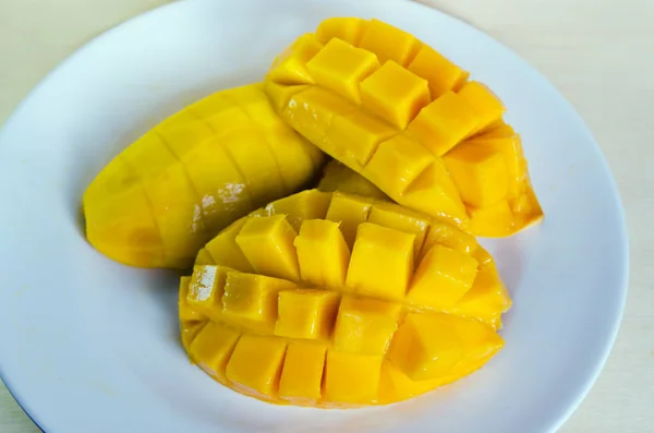 Mango-Frucht auf dem Teller in Scheiben geschnitten und isoliert auf Holz Hintergrund — Stockfoto