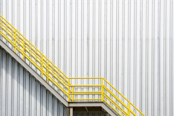 The yellow fire escape stair with the factory wall