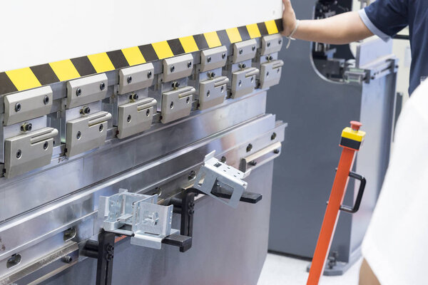 Техник использует гидравлический станок для гибки. 