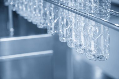 Evcil hayvan şişeleri doldurmak için taşıma bandında asılı..