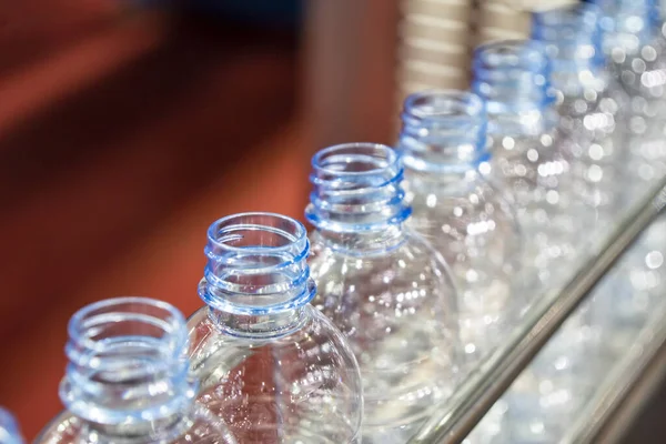 The PET bottles in the rail on the conveyor belt .