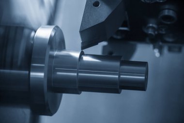 Metal işlemde kullanılan Cnc torna makinesi açık mavi sahnede metal şaft parçalarını kesiyor. Cnc dönüşüm makinesi tarafından çalışan yüksek teknolojili metal işleme .