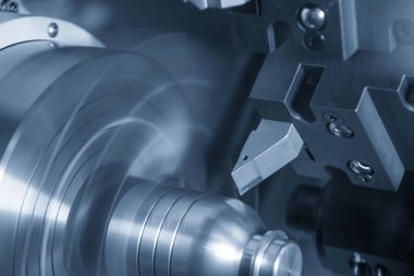 Metal işlemde kullanılan CNC torna makinesi açık mavi sahnede metal şaft parçalarını kesiyor. CNC dönüşüm makinesinin yüksek teknolojili metal işlemesi .