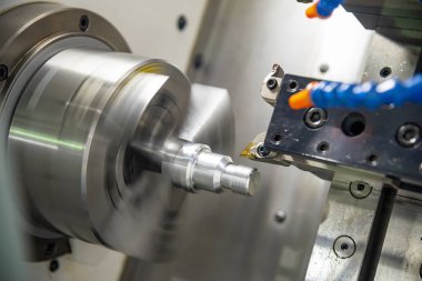 Metal işlemde kullanılan Cnc torna makinesi açık mavi sahnede metal şaft parçalarını kesiyor. Cnc dönüşüm makinesi tarafından çalışan yüksek teknolojili metal işleme .