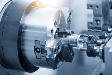Çok taretli Cnc torna makinesi açık mavi sahnede alüminyum tüp parçalarını kesiyor. Cnc dönüşüm makinesinin yüksek teknolojili metal çalışması.