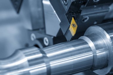 Metal işlemde kullanılan CNC torna makinesi açık mavi sahnede metal şaft parçalarını kesiyor. CNC dönüşüm makinesinin yüksek teknolojili metal işlemesi .