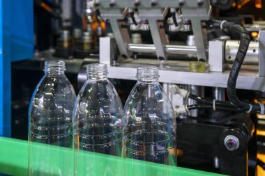 Su fabrikasındaki işlemleri tamamlamak için taşıma bandındaki korkuluktaki evcil hayvan şişeleri. Fabrikadaki otomatik doldurma makinesinin içme suyu üretim süreci.. 