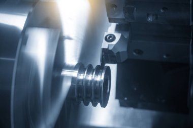 CNC torna makinesi kanalı aydınlatma efektiyle metal makara parçalarını kesiyor. CNC dönüşüm makinesinin yüksek teknolojili metal işlemesi .