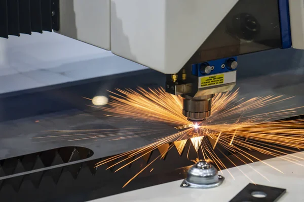 The fiber laser cutting machine cutting the sheet metal  plate with the sparkling light.  The hi-technology sheet metal manufacturing process by laser cutting machine.