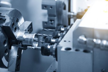 Çoklu görev yapan CNC torna makinesi İsviçre usulü pirinç şafta tıkırdıyor. CNC programı tarafından kontrol edilen yüksek teknolojili metal çalışma süreci