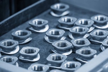 Açık mavi sahnedeki inşaat endüstrisinin özel amacı için özel fındık. Gevşek ceviz ve cıvata üretimi endüstrisi konsepti..