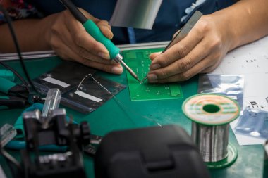 Yetenek operatörü PCB tahtasını lehimliyor. Elektronik endüstrisinde elle lehimleme işlemi. 