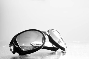 Eski ahşap masa üzerinde güneş gözlüğü kirli. Monoton etkisi.