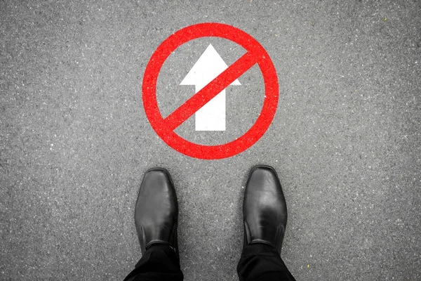 black shoes standing at do not go forward floor sign. Do not enter. Stop here.