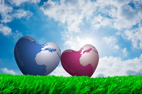 Love and valentine. Blue and pink earth hearts lean together on green grass. Cloudy shinny summer sky in background.