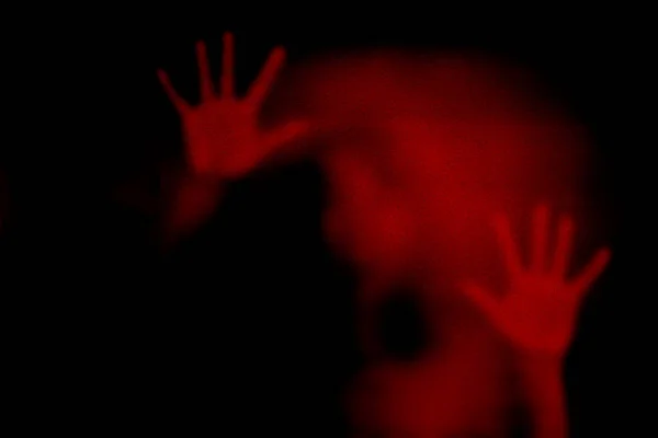 Red shadow of woman on the frosted glass representing dangerous, fear, help, haunting, horror,  scary, lockdown, infected, virus and plague.