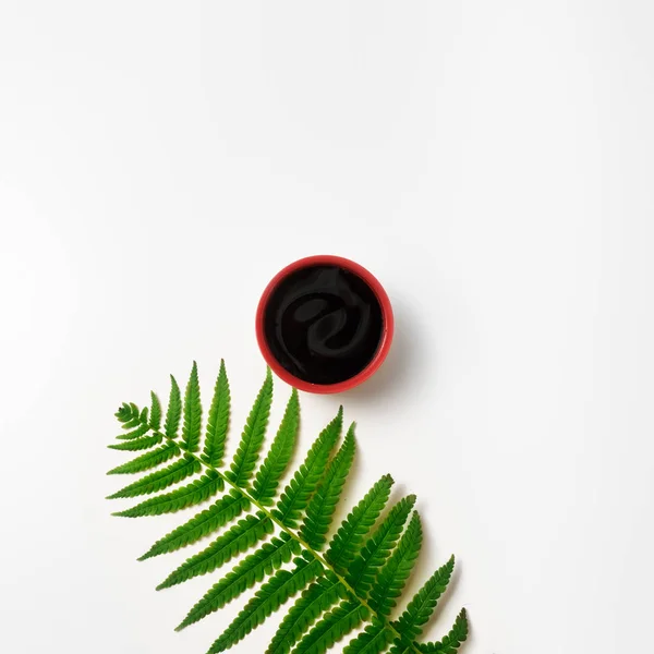 Минимализм. Красная чашка кофе среди листьев и цветов — стоковое фото
