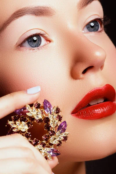 아름 다운 여자의 입술 밝은 패션 빨간 광택 있는 메이크업의 클로즈업. 매크로 립글로스 벚꽃 메이크업입니다. 웨딩 골드 다이아몬드 보석 입입니다. 쥬얼리 액세서리. — 스톡 사진