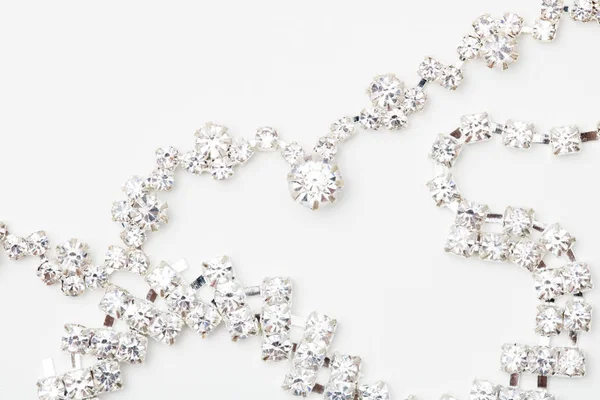 Un hermoso halo de diamantes y un colgante de oro blanco cuelgan de una cadena. Collar de joyería fina aislado sobre un fondo blanco con sombra y reflexión — Foto de Stock
