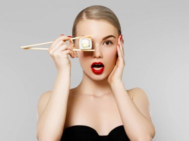 Diyet kavramı. Beslenme. Güzel gülümseyen kadın yemek suşi rulo çubuklarla. Moda portre, güzellik modeli kız ile mükemmel yüz makyaj, kırmızı dudaklar ve manikür. Sağlıklı Japon gıda