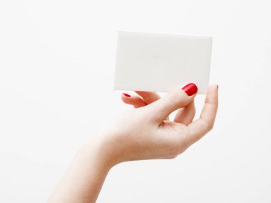 Düz yatıyordu, en iyi görünüm. Güzellik ve moda kavramı. Güzel eller kırmızı manikür ile. En az tarzı. Minimalist fotoğraf. Beyaz arka plan üzerinde kart tutan kız el ile soluk kompozisyon