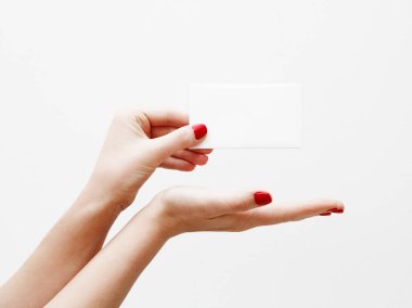 Düz yatıyordu, en iyi görünüm. Güzellik ve moda kavramı. Güzel eller kırmızı manikür ile. En az tarzı. Minimalist fotoğraf. Beyaz arka plan üzerinde kart tutan kız el ile soluk kompozisyon