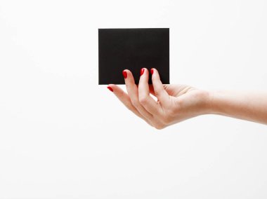 Düz yatıyordu, en iyi görünüm. Güzellik ve moda kavramı. Güzel eller kırmızı manikür ile. En az tarzı. Minimalist fotoğraf. Beyaz arka plan üzerinde indirim kartı tutan kız el ile kompozisyon