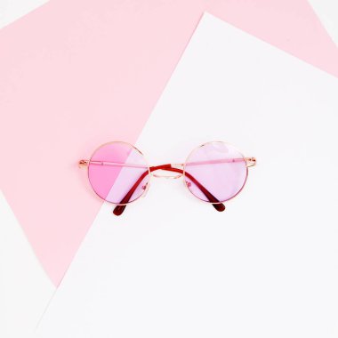 En az tarzı. Minimalist moda fotoğrafçılığı. Moda güneş gözlüğü. Yaz önümüzdeki kavramdır. Pastel bir arka plan, üstten görünüm pembe gözlüklerini. Modaya uygun en az tarzı renkli kağıt zemin ile